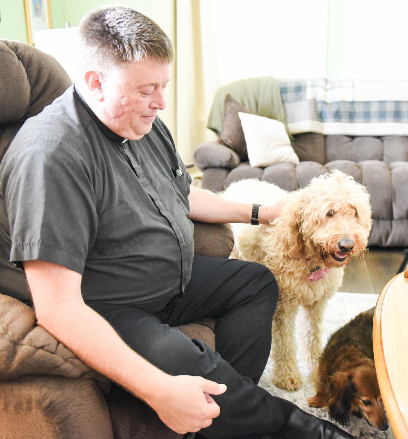 Father William Peckman, pastor of Immaculate Conception Parish in Macon, St. Mary Parish in Shelbina and the Mission of Sacred Heart in Bevier, entertains Buddy, a wire-haired Dachshund, and Molly, a Goldendoodle, in the St. Mary Parish Rectory.